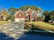 Beautiful two-story red brick home with a manicured lawn, a two-car garage, and mature trees at 3381 Walkers Ridge Rd, Dacula, GA 30019
