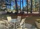 Cozy outdoor patio with table and chairs surrounded by a beautifully landscaped backyard and tall trees at 3381 Walkers Ridge Rd, Dacula, GA 30019