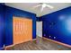 Bedroom with blue walls, wood-look floors, orange closet doors, ceiling fan, and white trim at 6498 Stonelake Sw Pl, Atlanta, GA 30331