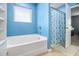 Bathroom featuring blue walls, a white tub, and a patterned shower curtain, with a view into the main bedroom at 2126 Sawgrass Dr, Hampton, GA 30228