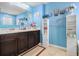 Well-lit bathroom with blue walls, double sinks, and white shelving for storage and decorative items at 2126 Sawgrass Dr, Hampton, GA 30228
