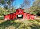 Exterior of a bright red barn with a classic design, surrounded by green grass and trees at 3889 Pineybrook Dr, Loganville, GA 30052