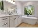 Bright bathroom features white cabinets, wood floors, a soaking tub, black hardware, and natural light at 551 Lees Mill Rd, Fayetteville, GA 30214