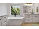 Bright bathroom with a soaking tub, natural light, white cabinets, and a glass-enclosed shower at 551 Lees Mill Rd, Fayetteville, GA 30214