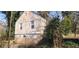 A home's side exterior with a partial brick foundation and surrounding overgrowth at 1497 Clermont Ct, Atlanta, GA 30344
