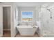 Bright bathroom featuring a soaking tub, a shower, and a large window at 149 Manor Lane, Woodstock, GA 30188