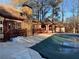 Backyard view showcasing a covered pool, stone chimney, and wooden deck against a backdrop of tall trees at 904 Wentworth Ct, Alpharetta, GA 30022