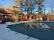 Backyard view showcasing a covered pool, stone chimney, and wooden deck against a backdrop of tall trees at 904 Wentworth Ct, Alpharetta, GA 30022