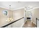 Upstairs hallway featuring elegant chandelier, white wainscotting, and doorway to a bedroom at 2460 Millwater Crossing Xing, Dacula, GA 30019