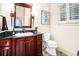 Cozy bathroom with dark wood vanity, decorative mirror, sconces, and patterned tile flooring at 3000 Rivermeade Nw Dr, Atlanta, GA 30327