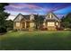Stunning brick home features manicured lawn, beautiful landscaping, and inviting front porch at 102 Glenmill Way, Woodstock, GA 30188