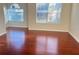 An empty living room with hardwood floors is naturally lit from two bright windows at 1418 Brookside Manor Ct, Tucker, GA 30084