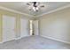 Spacious bedroom with neutral carpet, a ceiling fan, and three white doors at 1755 Riverpark Dr, Dacula, GA 30019