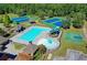 Aerial view of the community pool, tennis courts, playground, and mature trees creating an inviting outdoor space at 1755 Riverpark Dr, Dacula, GA 30019