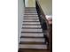 Elegant staircase with dark wood treads, white risers, and decorative wrought iron railings at 1755 Riverpark Dr, Dacula, GA 30019
