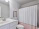 Bright bathroom with a single vanity, toilet, and tub with a pink and white shower curtain at 5315 Hidden Valley Ln, Cumming, GA 30028
