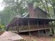 Charming cabin-style home with a wraparound porch surrounded by lush trees at 6245 Bannister Rd, Cumming, GA 30028