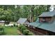Exterior of a charming rustic home with a metal roof, featuring a covered carport and a verdant, tree-filled yard at 6245 Bannister Rd, Cumming, GA 30028