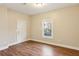 An empty bedroom featuring neutral walls, wood floors, and a window to the outside at 645 Trailmore Pl, Roswell, GA 30076