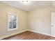 Neutral-painted bedroom with wood floors featuring a window view of the back stairs at 645 Trailmore Pl, Roswell, GA 30076