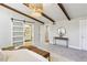 Inviting bedroom featuring exposed wooden beams, modern lighting, and a sliding barn door to the ensuite bathroom at 645 Trailmore Pl, Roswell, GA 30076