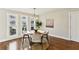 Bright dining room with hardwood floors, a round table, four chairs, and three windows providing ample natural light at 645 Trailmore Pl, Roswell, GA 30076