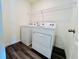 Modern laundry room featuring a white washer and dryer with overhead shelving and luxury vinyl flooring at 7722 Sudbury Cir, Covington, GA 30014