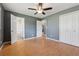 A gray bedroom is shown with a ceiling fan, wood floors, and a large closet at 401 Cabriolet Ct, Mcdonough, GA 30253