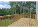 Wooden deck with railing overlooking grass backyard and green lush forest at 553 Somersby Dr, Dallas, GA 30157