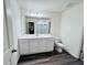 Bathroom with a double sink vanity and large mirror over dark wood-look flooring at 7714 Sudbury Cir, Covington, GA 30014