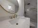 This bathroom showcases a modern design with marble-look shower tile, gold fixtures, and a contemporary circular mirror at 8168 Spring Ct, Riverdale, GA 30274