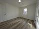 Clean, empty bedroom features wood-look flooring, a window, and door with black hardware at 8168 Spring Ct, Riverdale, GA 30274