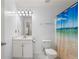 Bright bathroom with a single sink vanity, white toilet, and tub with ocean-themed shower curtain at 1893 Tulip Petal Rd, Auburn, GA 30011