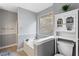 Well-lit bathroom features gray walls, white cabinets, tub, window, and tiled floor at 13 Greystone Nw Ln, Cartersville, GA 30121