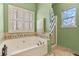 Bathroom featuring tiled walls, a soaking tub, and a decorative stained glass window at 134 Paces Lakes Overlook, Dallas, GA 30157