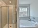 Bright bathroom with glass shower door and a large white bathtub overlooking a window at 3328 Sir Gregory Mnr, Lawrenceville, GA 30044