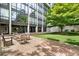 Charming courtyard seating area with brick pavers and lush landscaping in front of a modern building with large windows at 2575 Peachtree Ne Rd # 10D, Atlanta, GA 30305