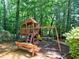 A fun wooden playground with swings, slide, and climbing features, set in a spacious wooded backyard at 7440 Princeton Trce, Sandy Springs, GA 30328