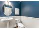 A stylish powder room with dark blue walls, white wainscoting, and a pedestal sink at 1658 Duncan Nw Dr, Atlanta, GA 30318