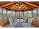 A cozy gazebo interior boasts comfortable seating around a glass table, perfect for relaxation with serene views at 340 Ruby Forest Pkwy, Suwanee, GA 30024