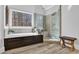 Modern bathroom featuring a soaking tub, tiled shower, wood-look floors, and a large window at 455 Emerald Lake Path, Sugar Hill, GA 30518