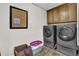 Well-equipped laundry room with washer, dryer and overhead cabinets at 455 Emerald Lake Path, Sugar Hill, GA 30518