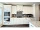 Modern kitchen with stainless steel double ovens, gas cooktop, and gray backsplash at 1411 Wisteria Wall Dr, Suwanee, GA 30024