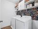 Convenient laundry room with modern washer and dryer, decorative wallpaper, and shelving at 3180 Spicy Cedar Ln, Lithonia, GA 30038