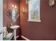 Stylish powder room features a pedestal sink, decorative mirror, and elegant wall sconces with a window at 3180 Spicy Cedar Ln, Lithonia, GA 30038