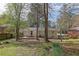 View of backyard and home's rear facade, showcasing a brick home, patio area, and a sprawling yard with mature trees at 3532 Dial Dr, Stone Mountain, GA 30083