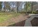Large, fenced backyard featuring a concrete patio, mature trees, and a spacious grassy area, perfect for outdoor activities at 3532 Dial Dr, Stone Mountain, GA 30083