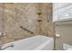 Relax in this bathroom, featuring a tub with safety bars, tiled floors and stone-look walls at 3532 Dial Dr, Stone Mountain, GA 30083