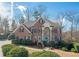 Charming brick home featuring a manicured lawn, lush landscaping, and a welcoming light blue front door at 6195 Mountainwell Dr, Roswell, GA 30075