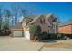Spacious three-car garage with a brick exterior, a large driveway, and mature landscaping at 6195 Mountainwell Dr, Roswell, GA 30075